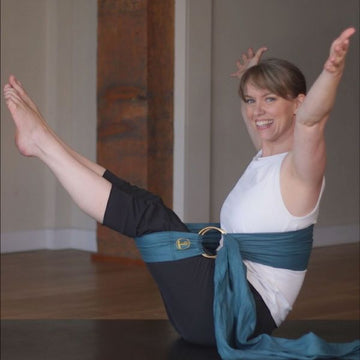 Women with arms and legs in the air using Teal Earth to Ether Lotus Wrap to support with legs